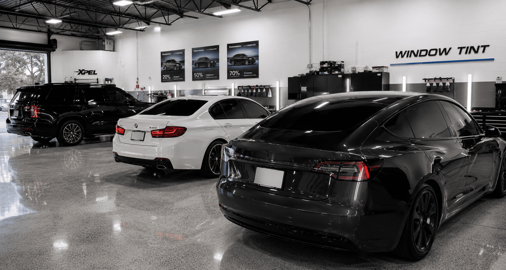 Professional window tint shop floor with BMW, Tesla, and SUV lined up for tinting