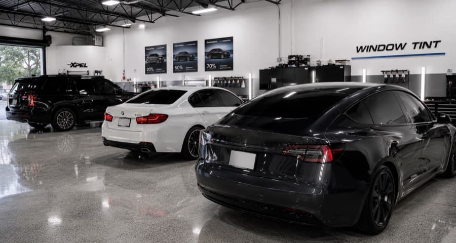 Professional window tint shop floor with BMW, Tesla, and SUV lined up for tinting